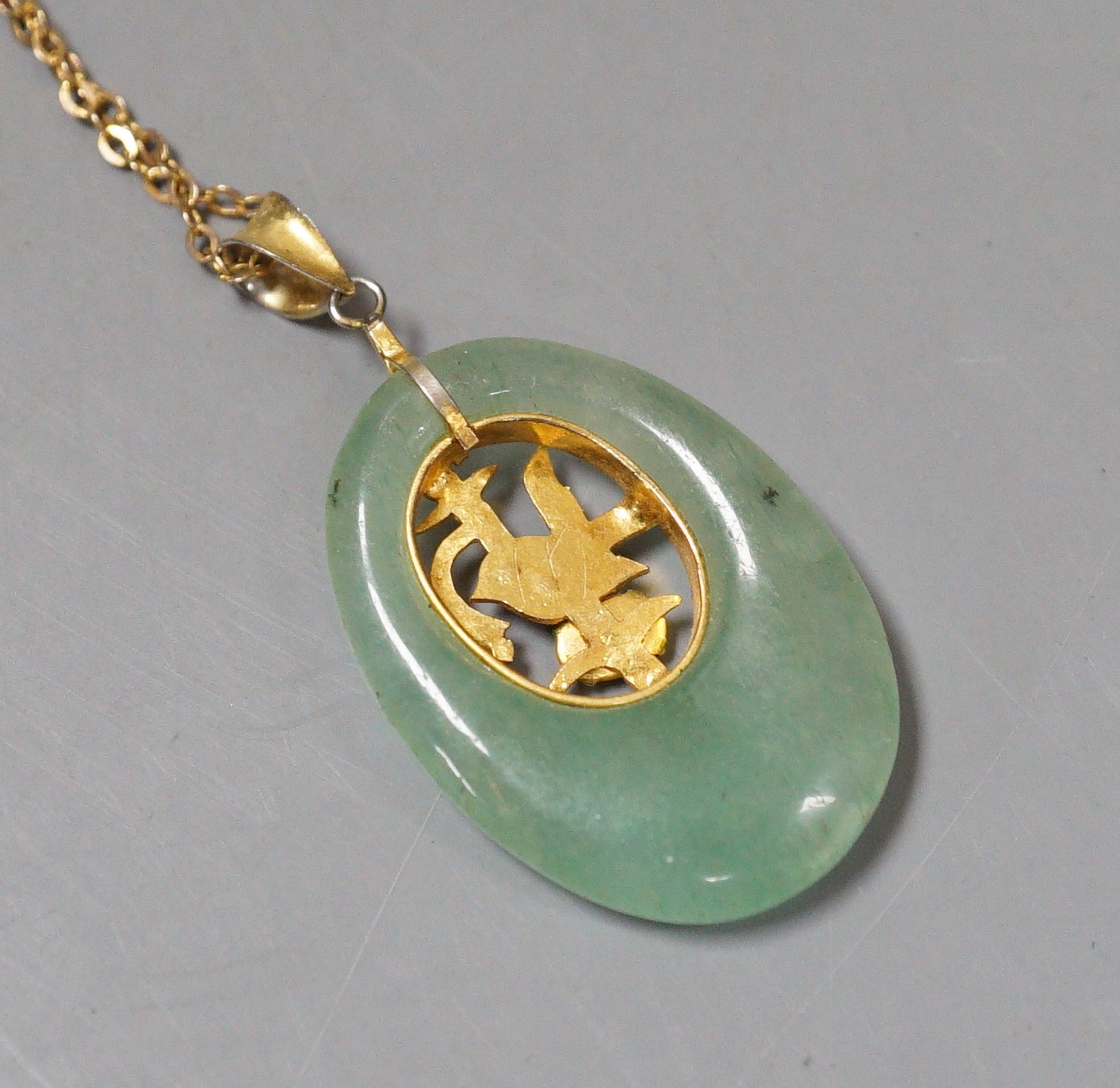 A gilt metal and gem set mounted oval adventurine quartz? pendant, 36mm, on a 9ct chain, 46cm, gross weight 9.4 grams.